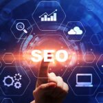 Bir kişinin parmağıyla "SEO" yazısına dokunduğu, etrafında dijital pazarlama ve internet ikonlarının yer aldığı, mavi arka planlı dijital arayüz.
